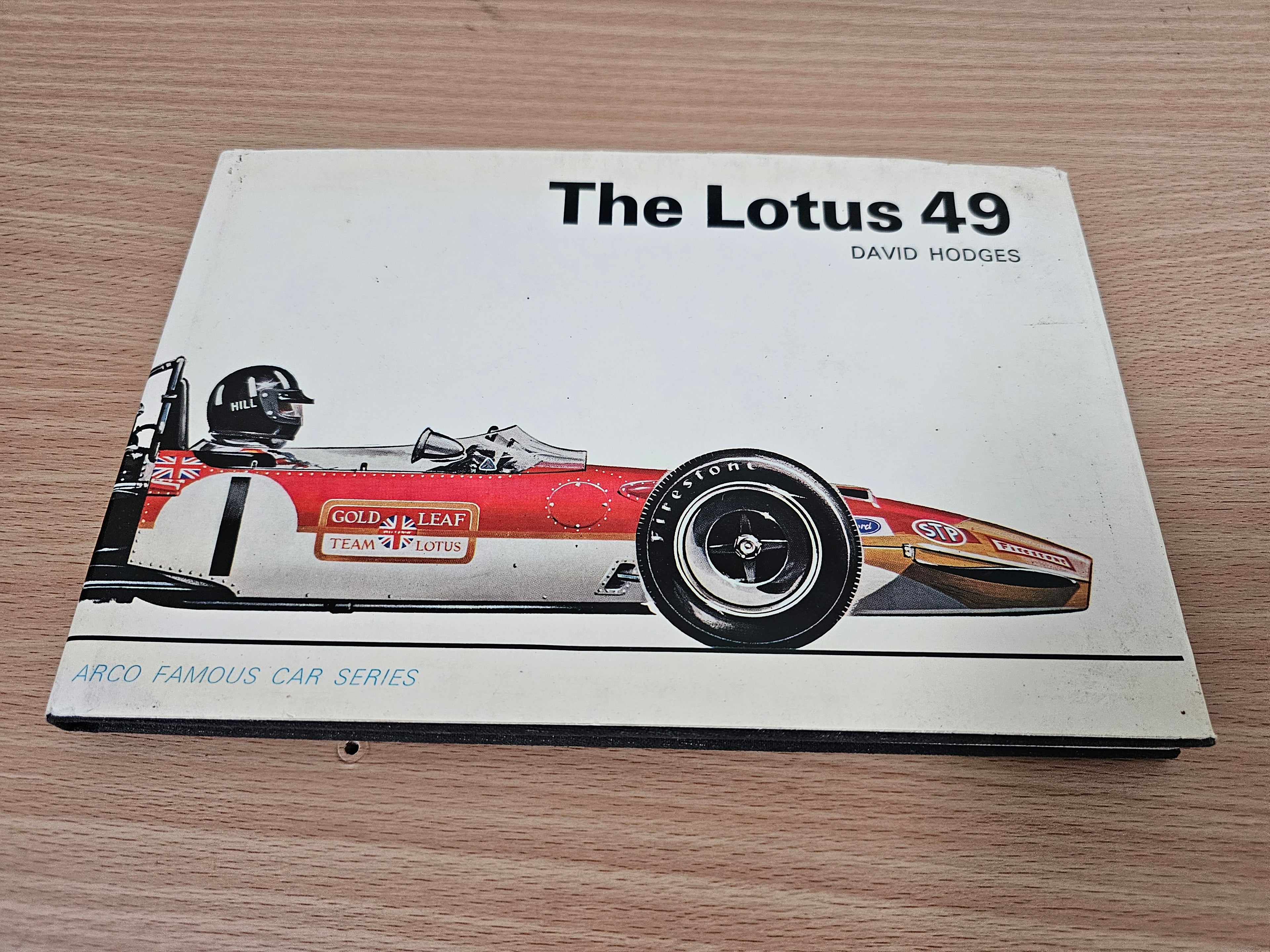 Book cover on surface, showing The Lotus 49 title and red race car artwork