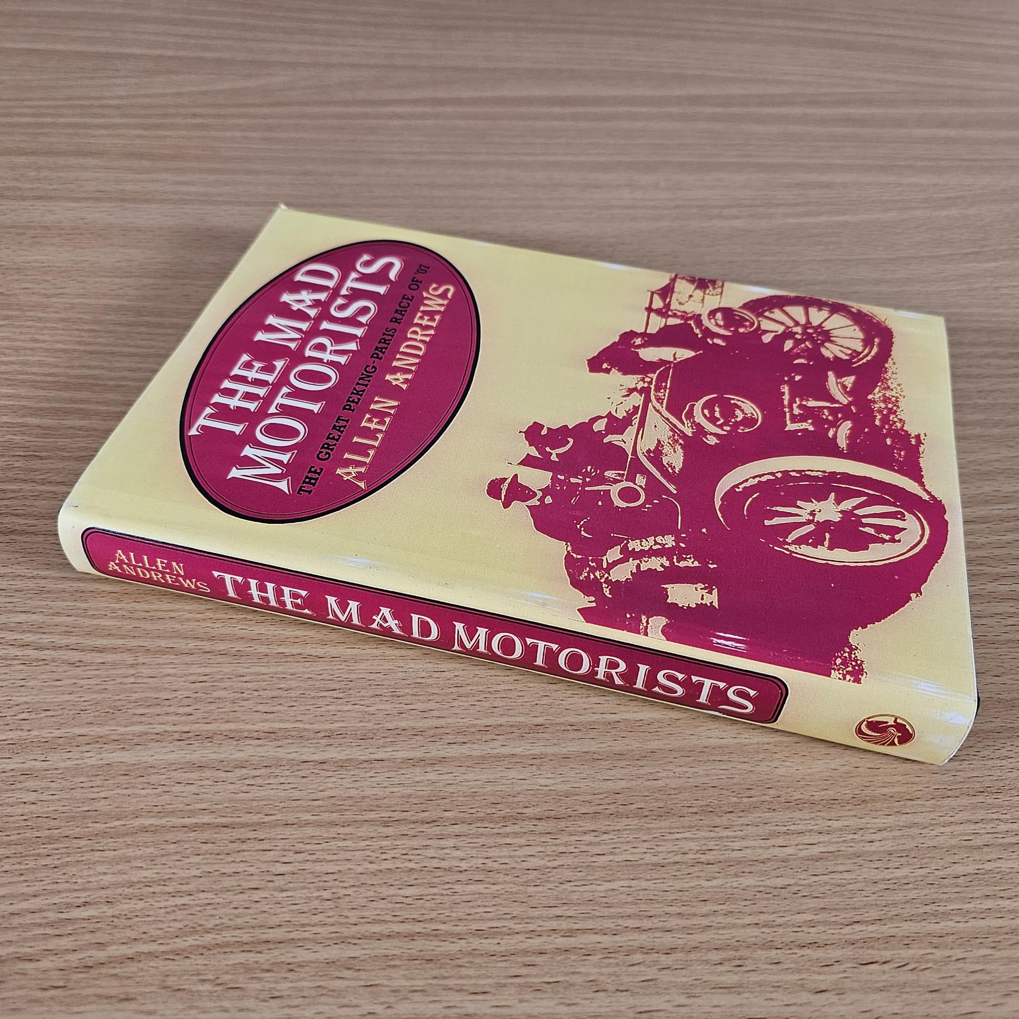 Vintage hardcover book lying flat with maroon title oval and maroon race art on pale cover