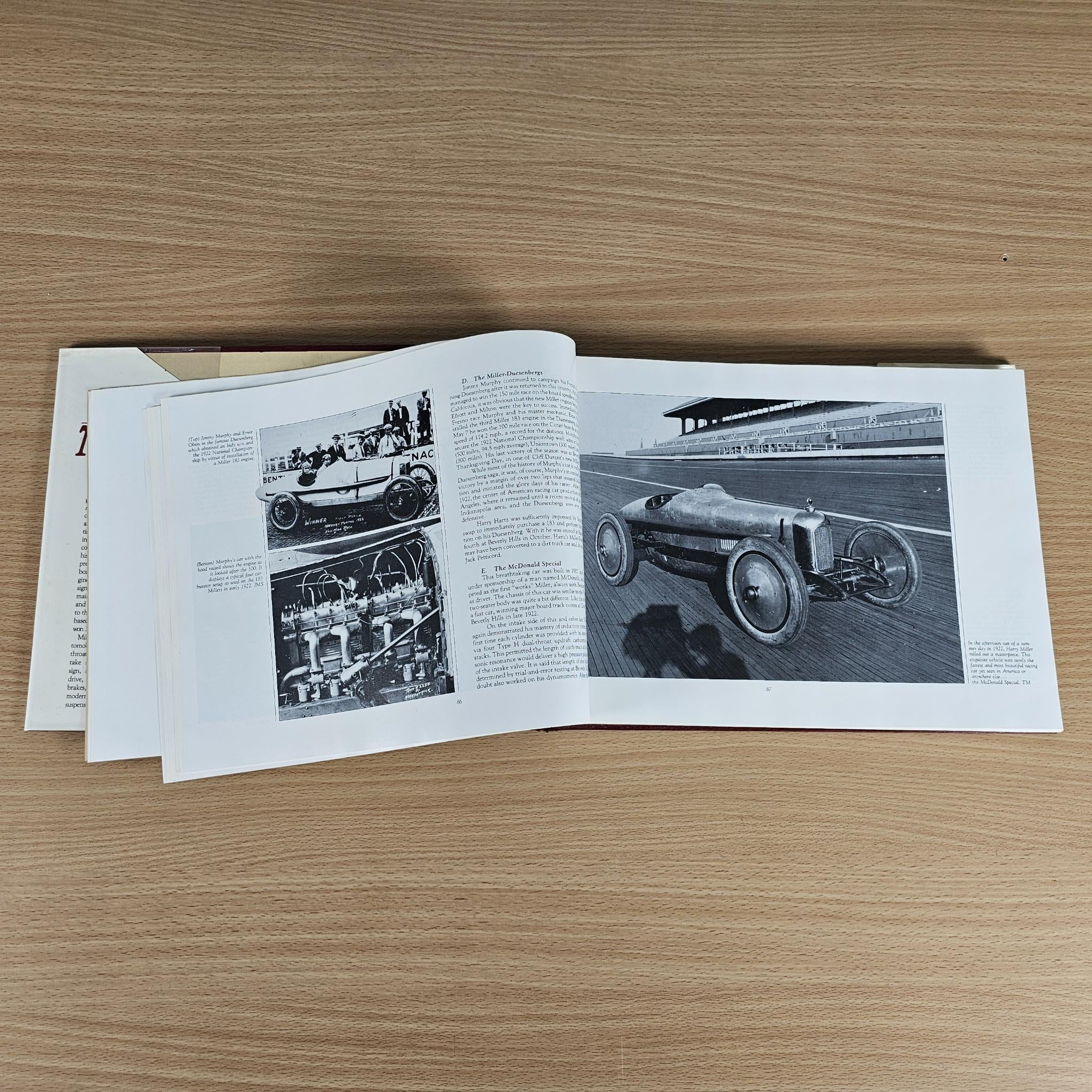 Open technical history book with black-and-white vehicle photos and text pages