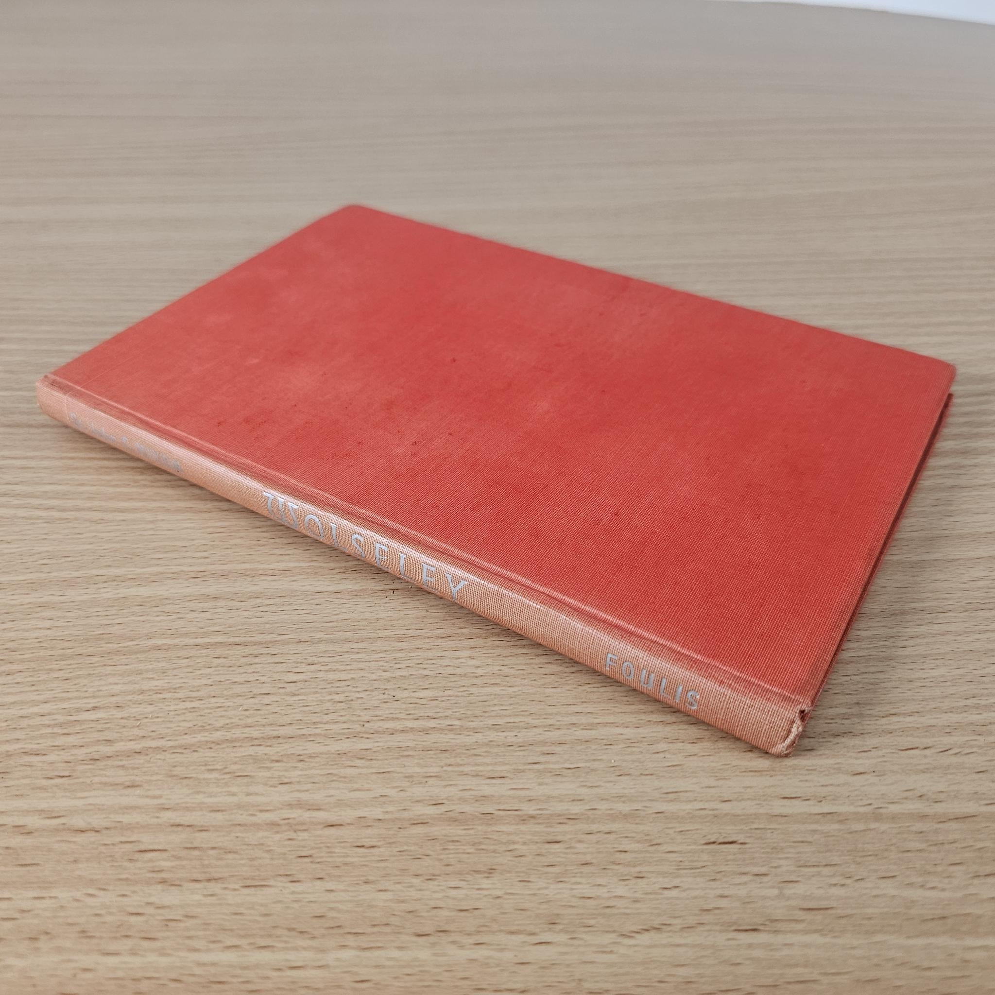 Red hardcover book with worn spine and pale title on the bottom edge