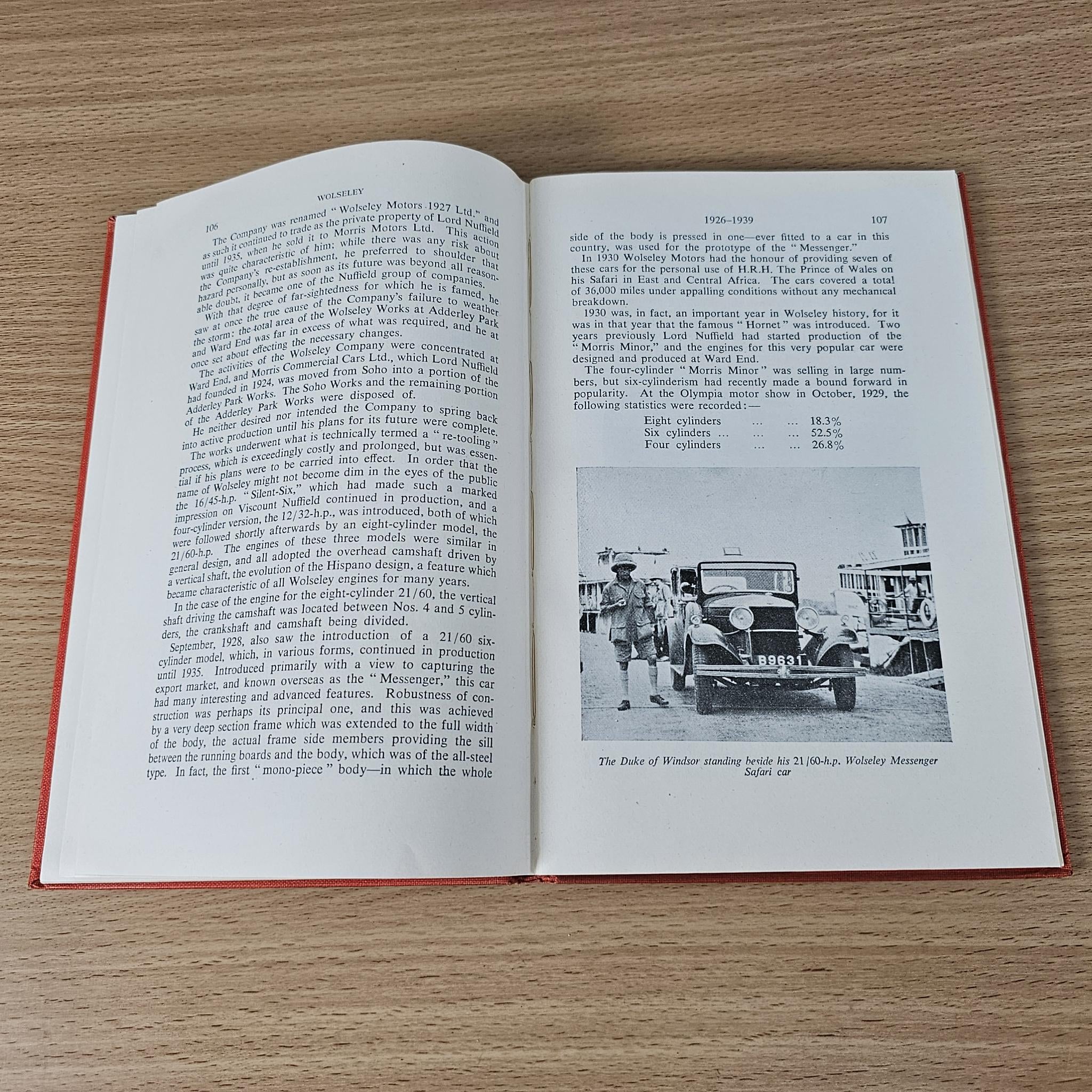 Open book with text on both pages and a vintage vehicle photo near the bottom-right