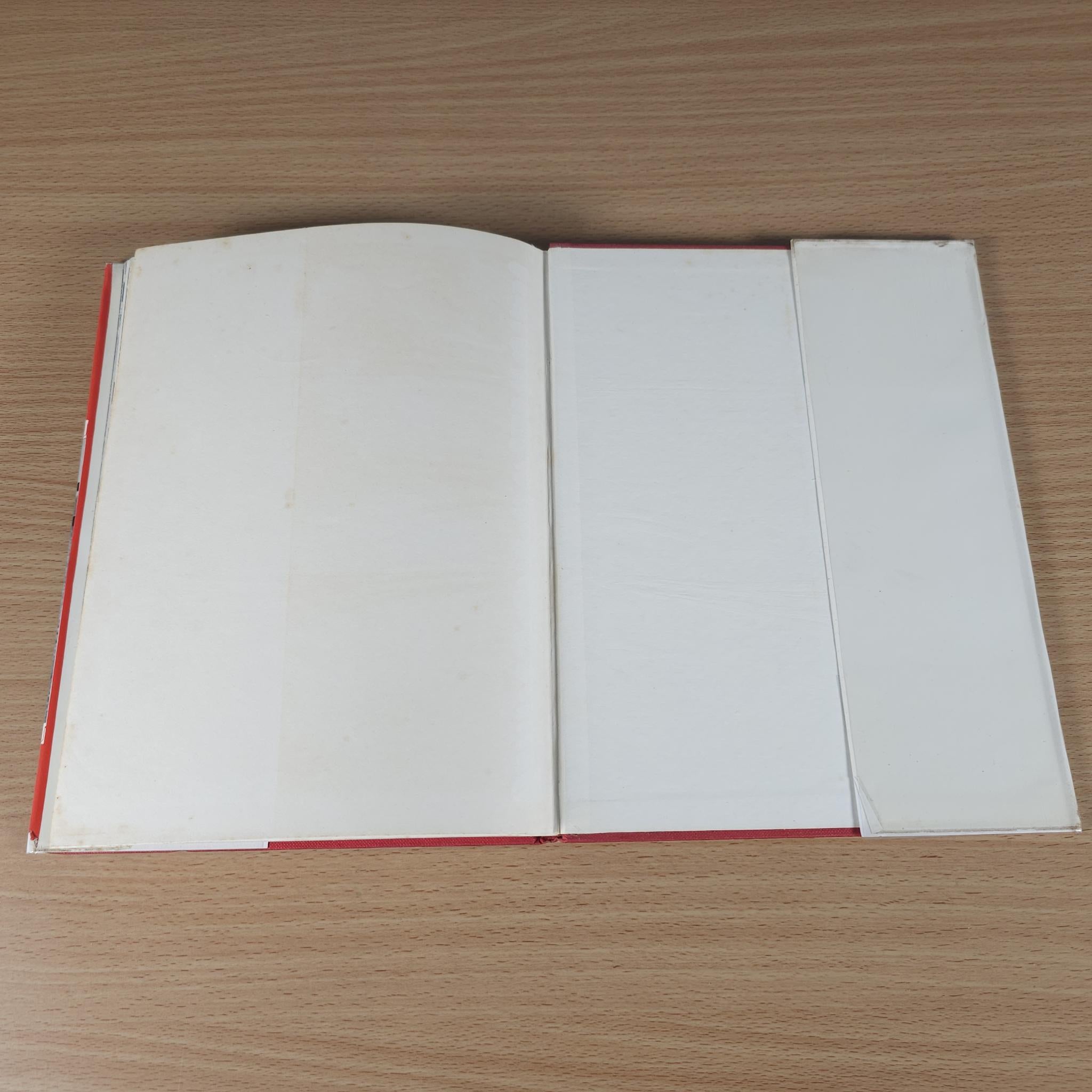 Vintage motor racing book, open to blank pages with red-edged binding.