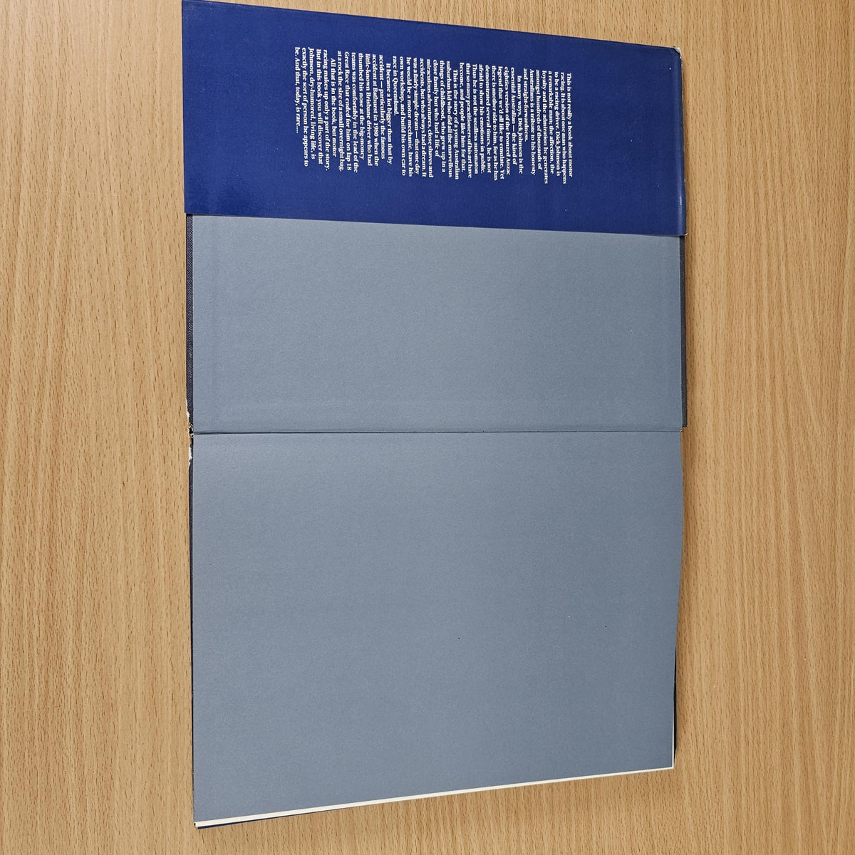 Closed hardcover book showing blue back cover sections and smooth gray spine panel