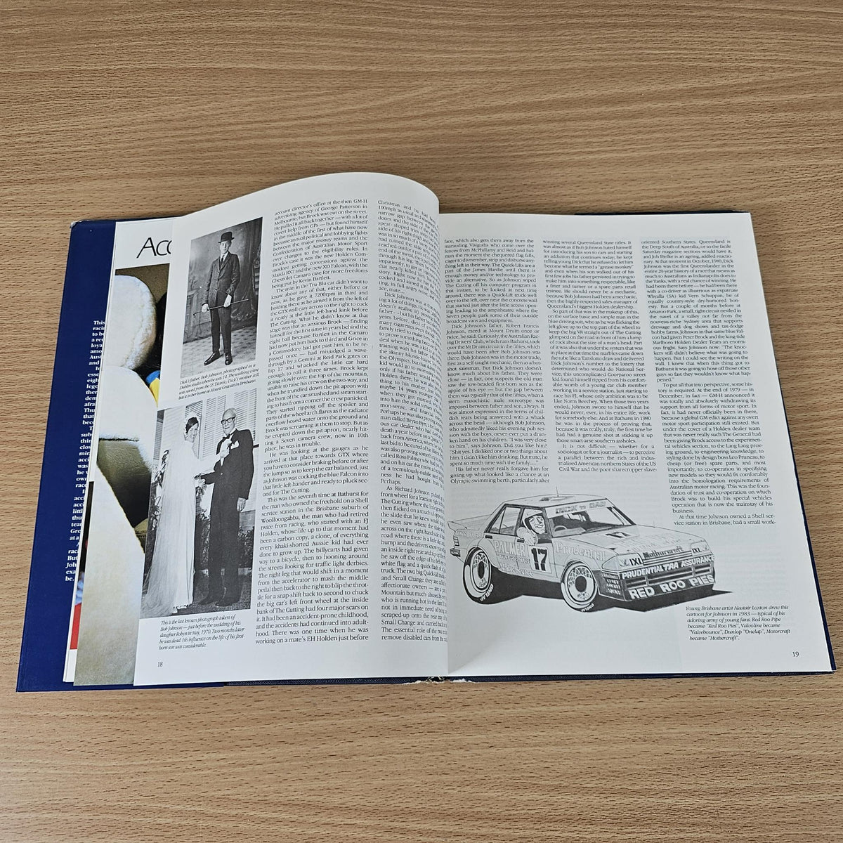 Opened hardcover book with car illustration, black-and-white photos, and dense text