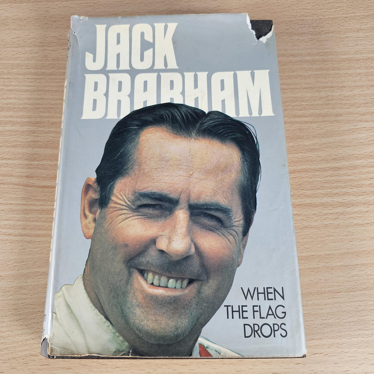 Hardcover autobiography book cover with Jack Brabham portrait and title “When the Flag Drops”