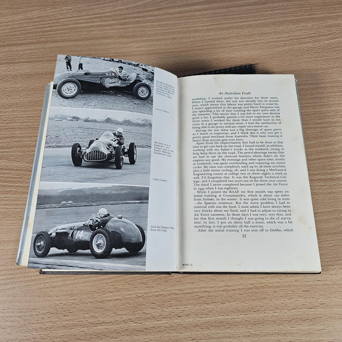 Open hardcover book with black-and-white racing car photos and printed caption text