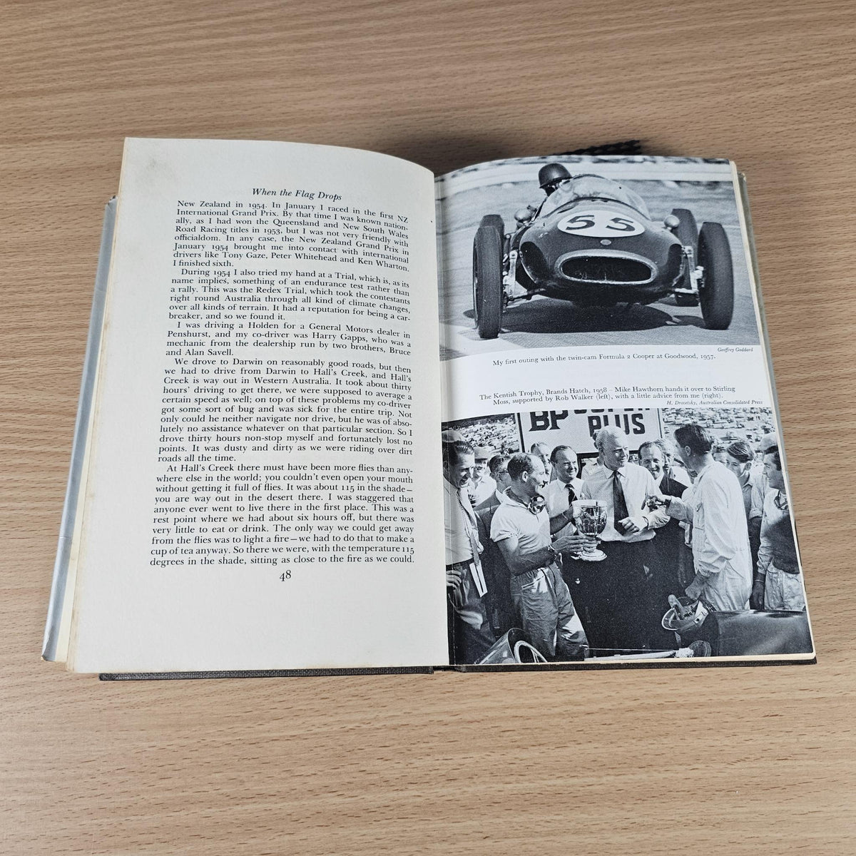 Open hardcover book pages with typewritten text and black-and-white racing photos