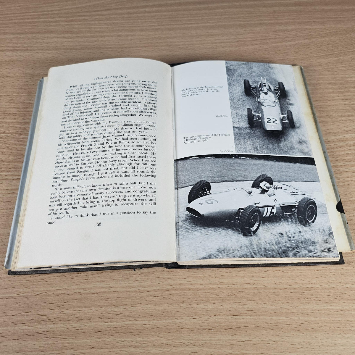 Open hardcover book with text pages and black-and-white racing car action photo