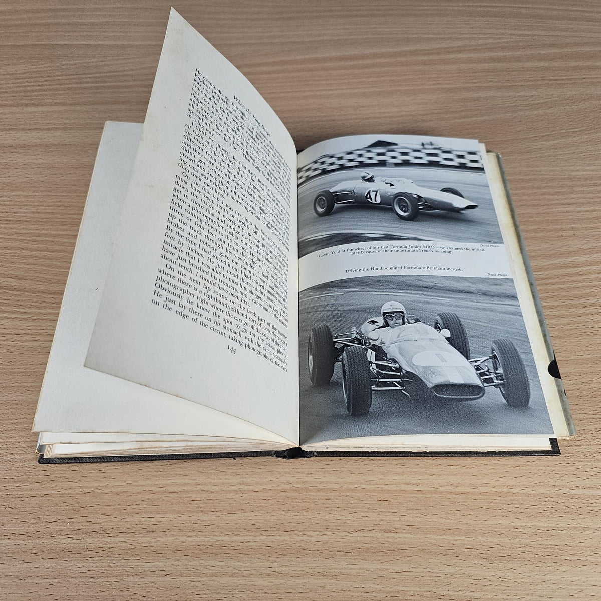 Open hardcover book with left text page and right photo of a race car on track