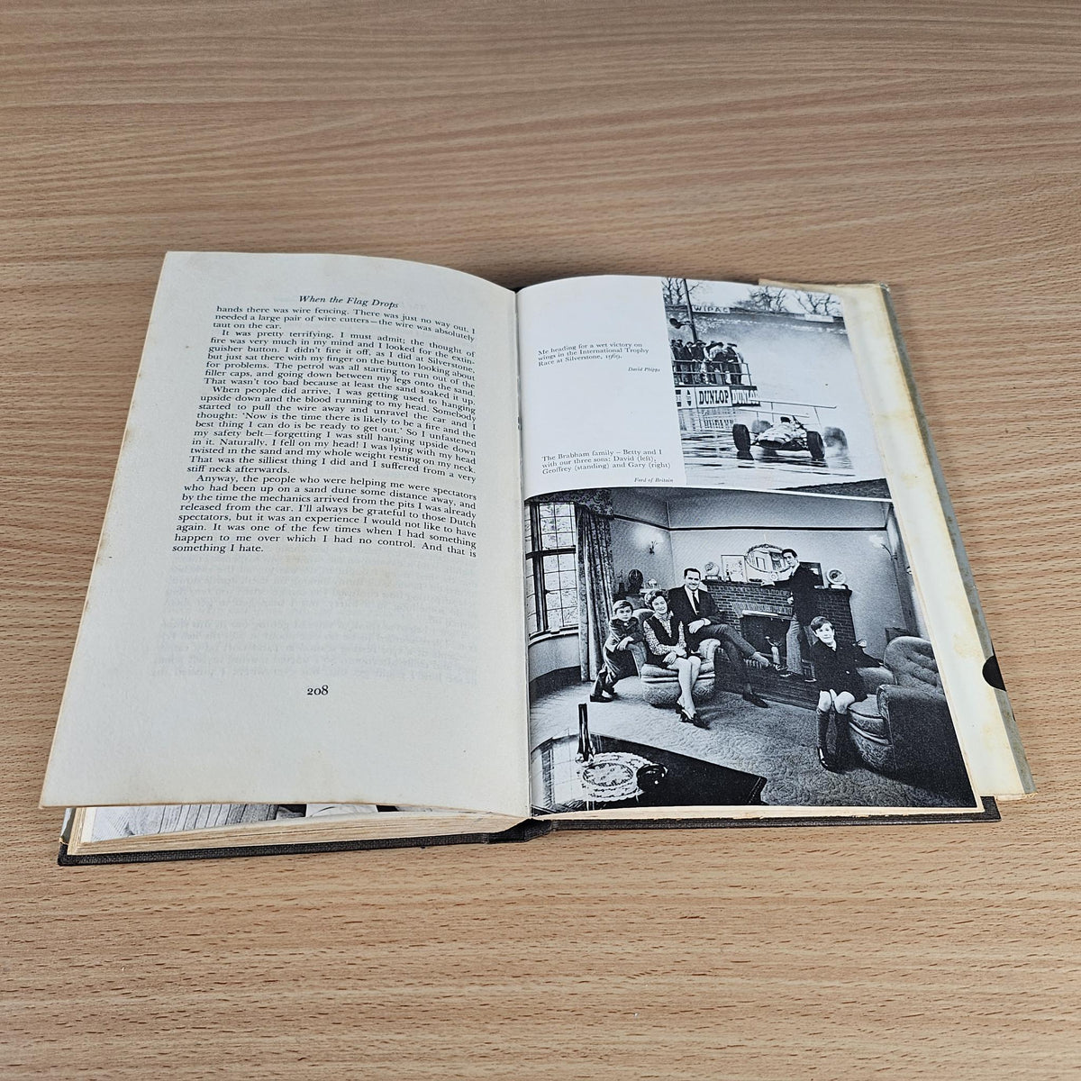 Open hardcover book with text pages and black-and-white photos, including a car inside image